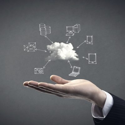 Hand drawn technology and computer icons around cloud with hand on gray background, cloud computing concept.